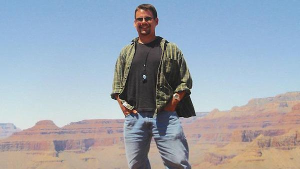 Brad stands casually on a rock platform overlooking the layers of the Grand Canyon.